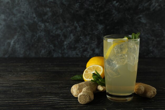 ginger ale drink in a glass with ginger and lemon at its one side on a wooden table.