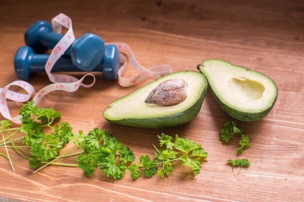 avocado with dumbbells and measuring tape placed on the floor, depicting the use of avocado in weight loss.