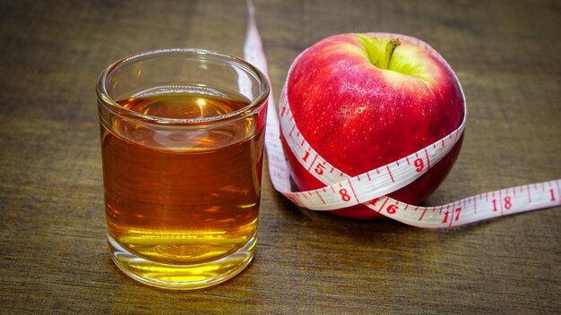 apple juice in a glass placed with an apple and measuring tape.