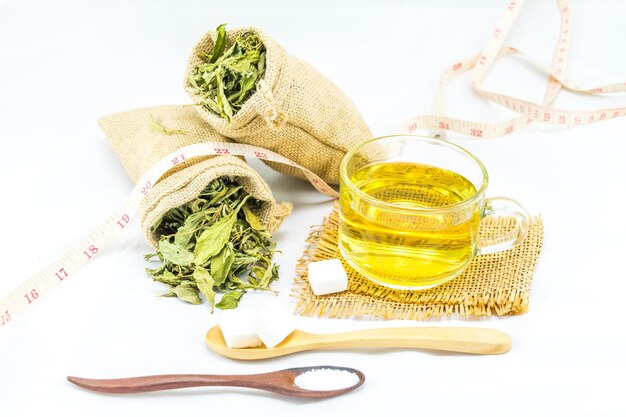 a cup of green tea with leaves in two small sacks