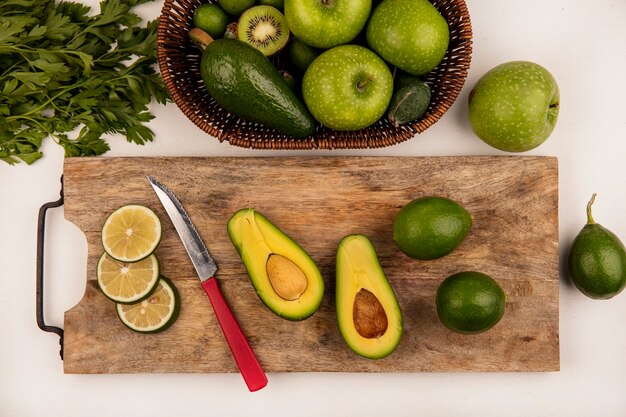 avocados placed on a cutting board with knife and some pieces of lemon.