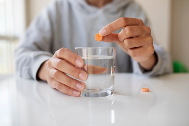 a person taking his medicine with a glass of water.