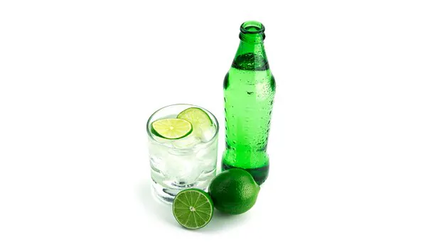 7-up bottle with a glass filled with 7-up drink, ice cubes and lemon slices.