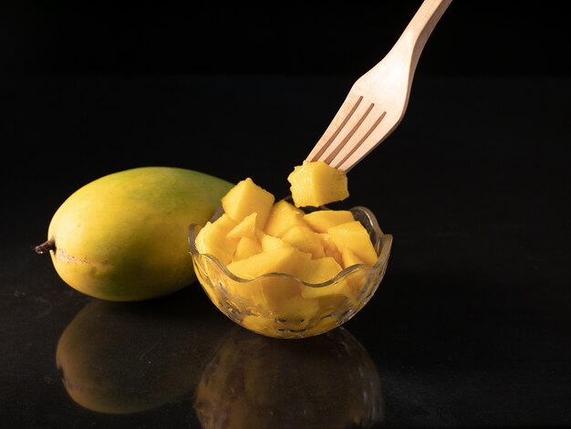 a mango with its slices in a glass bowl.