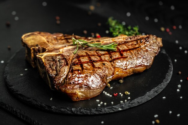 beef steak with seasonings on a black surface.
