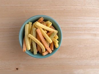 veggie straws in a blue bowl on wooden surface