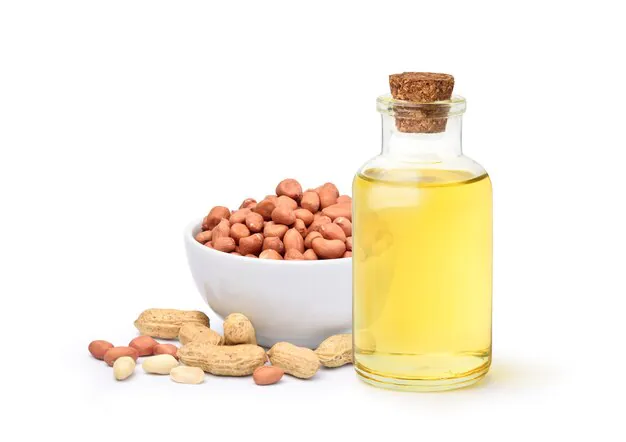 peanut oil in a glass bottle with peanuts in a bowl